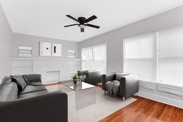 living room with ceiling fan, hardwood / wood-style floors, and a brick fireplace