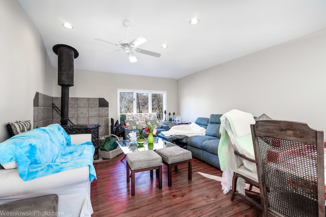 living room with a wood stove, ceiling fan, and dark wood-type flooring