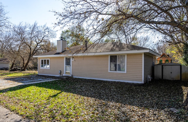 rear view of house with a lawn and a storage unit