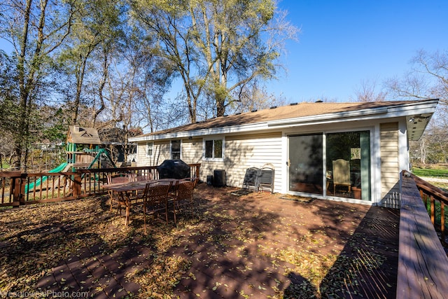 rear view of house with a playground and a wooden deck