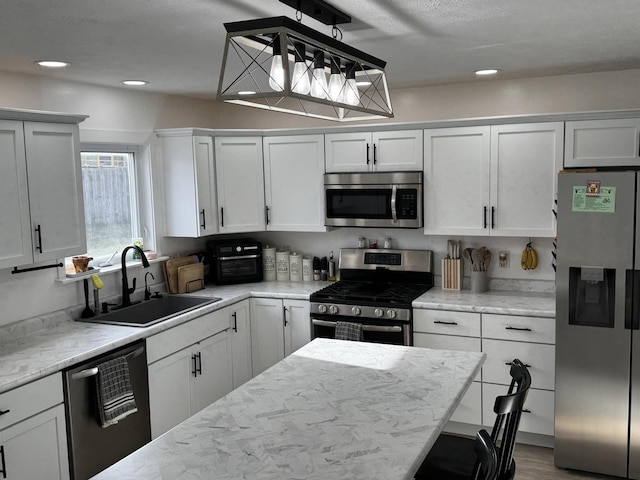 kitchen featuring pendant lighting, white cabinets, sink, appliances with stainless steel finishes, and a breakfast bar area