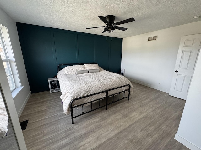 bedroom featuring ceiling fan, light hardwood / wood-style flooring, and a textured ceiling