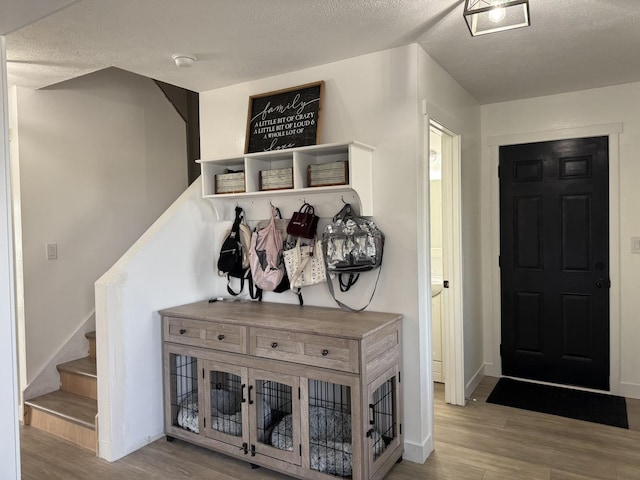 mudroom with light hardwood / wood-style floors and a textured ceiling