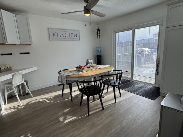 dining area with a textured ceiling, ceiling fan, and dark wood-type flooring