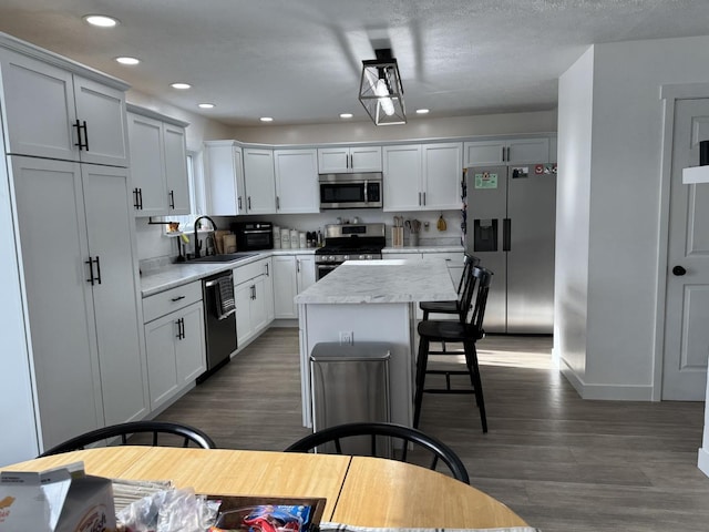 kitchen with sink, a kitchen island, dark wood-type flooring, and appliances with stainless steel finishes