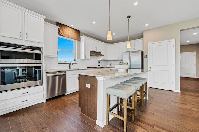 kitchen featuring white cabinetry, a center island, dark wood-type flooring, stainless steel appliances, and pendant lighting