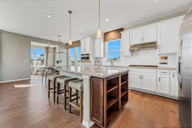 kitchen with white cabinets, a kitchen island, wood-type flooring, and hanging light fixtures