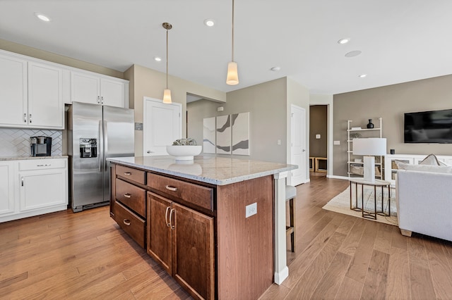 kitchen with decorative light fixtures, light wood-type flooring, white cabinetry, and stainless steel refrigerator with ice dispenser