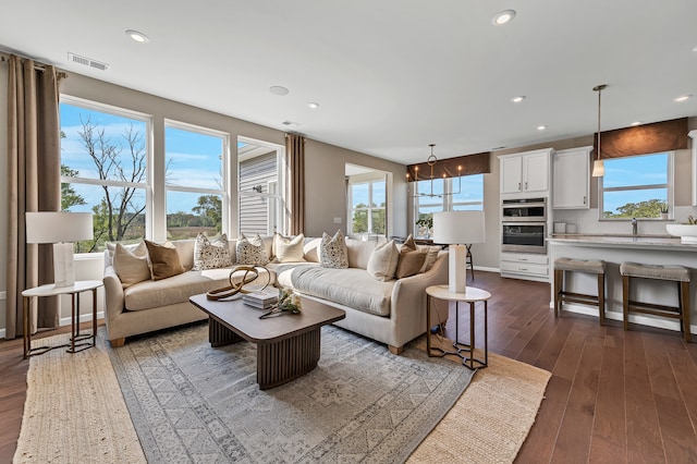 living room featuring dark hardwood / wood-style flooring, an inviting chandelier, a healthy amount of sunlight, and sink