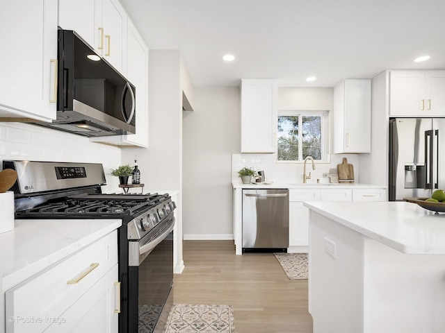 kitchen with white cabinetry, sink, stainless steel appliances, and light hardwood / wood-style floors