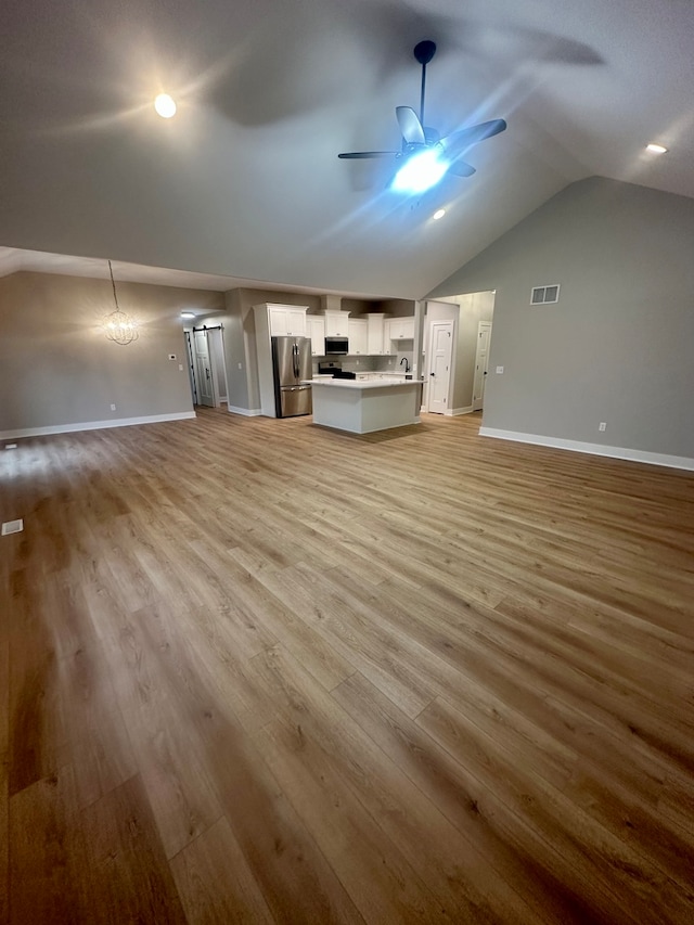 unfurnished living room with ceiling fan, vaulted ceiling, and light hardwood / wood-style flooring