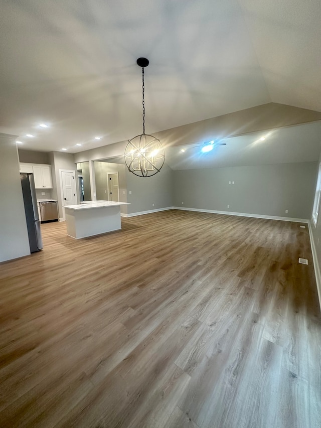 unfurnished dining area with a chandelier, vaulted ceiling, and light hardwood / wood-style flooring