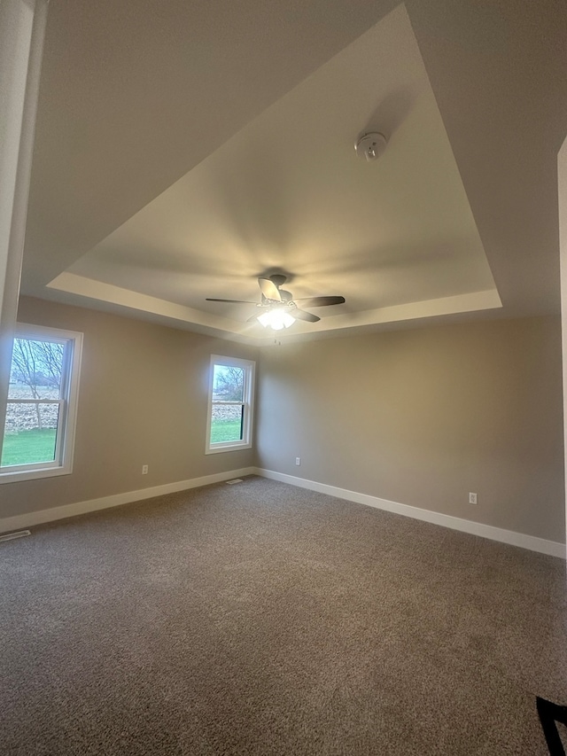 unfurnished room with carpet flooring, ceiling fan, and a tray ceiling