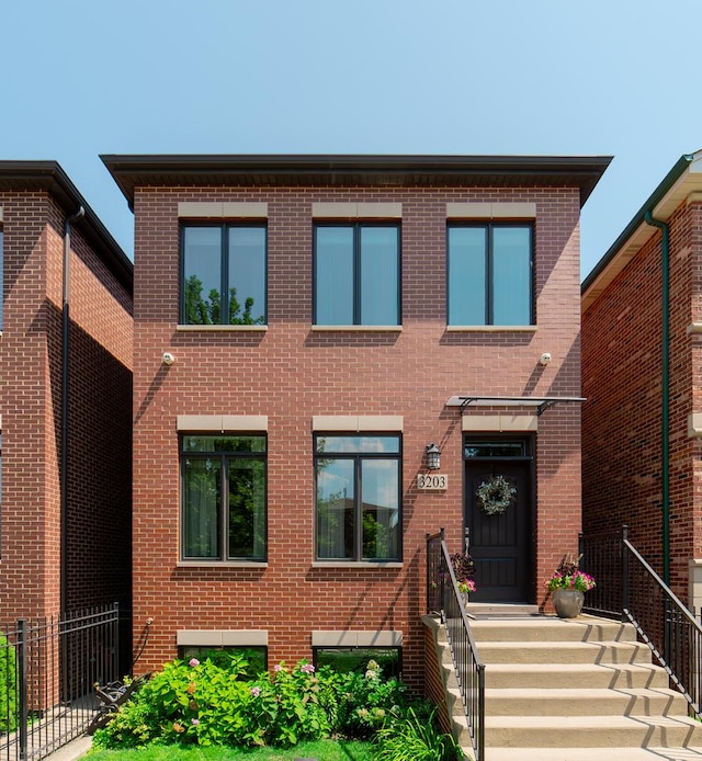 view of front of home featuring brick siding and fence