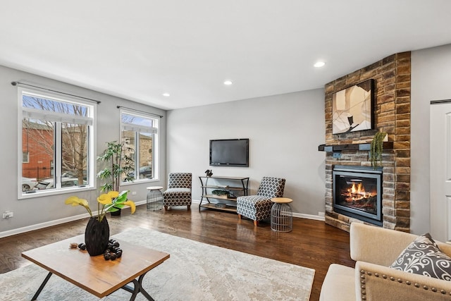 living area featuring a large fireplace, baseboards, wood finished floors, and recessed lighting