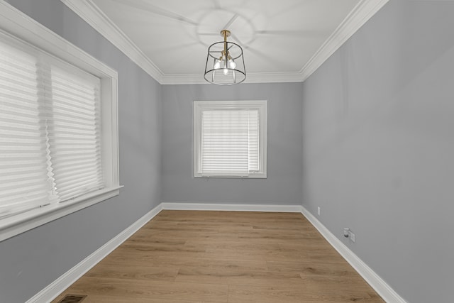 unfurnished room featuring a notable chandelier, light wood-type flooring, and ornamental molding