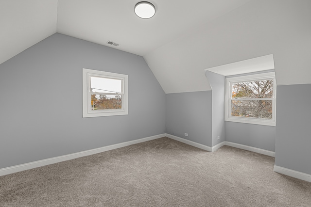 bonus room with carpet floors, a wealth of natural light, and vaulted ceiling