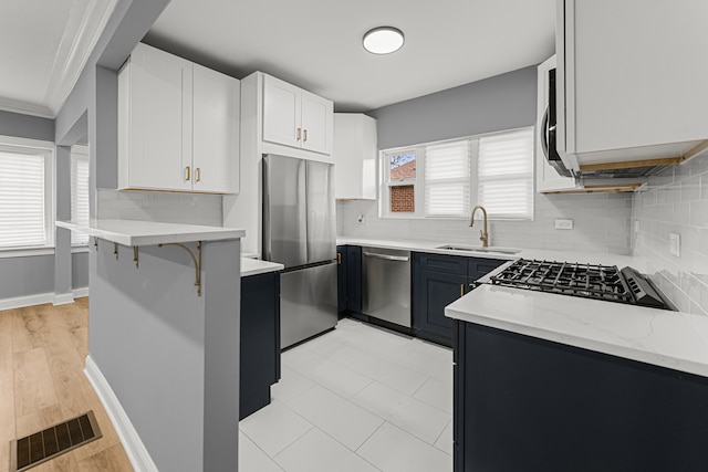 kitchen featuring tasteful backsplash, sink, white cabinets, and stainless steel appliances