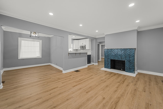 unfurnished living room with a fireplace, light hardwood / wood-style floors, and ornamental molding