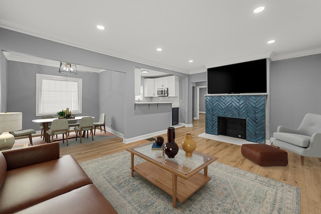 living room featuring a fireplace, a chandelier, light hardwood / wood-style flooring, and crown molding