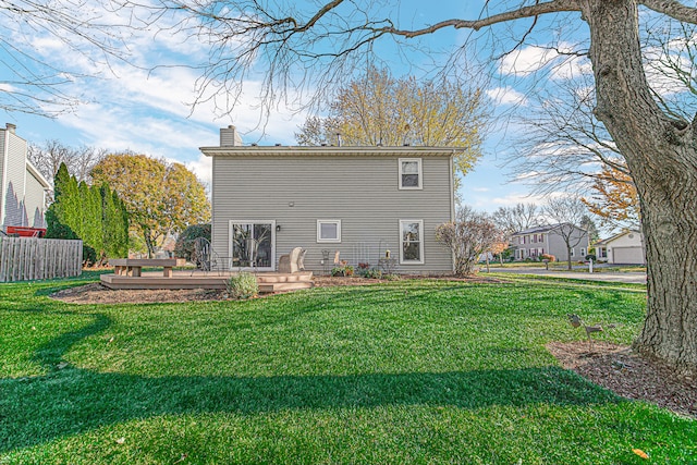 rear view of house featuring a lawn and a wooden deck