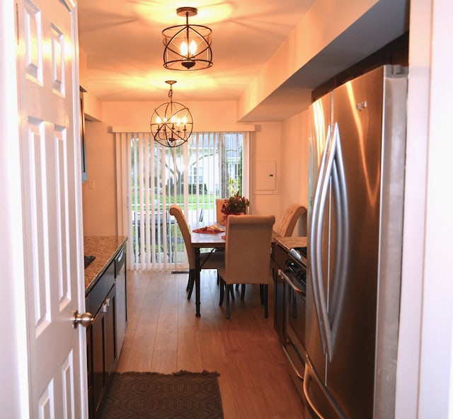 kitchen with stone counters, stainless steel appliances, a chandelier, pendant lighting, and light hardwood / wood-style floors