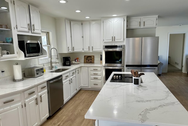 kitchen featuring light stone countertops, stainless steel appliances, sink, light hardwood / wood-style floors, and white cabinetry