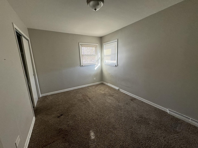 carpeted spare room featuring a baseboard heating unit