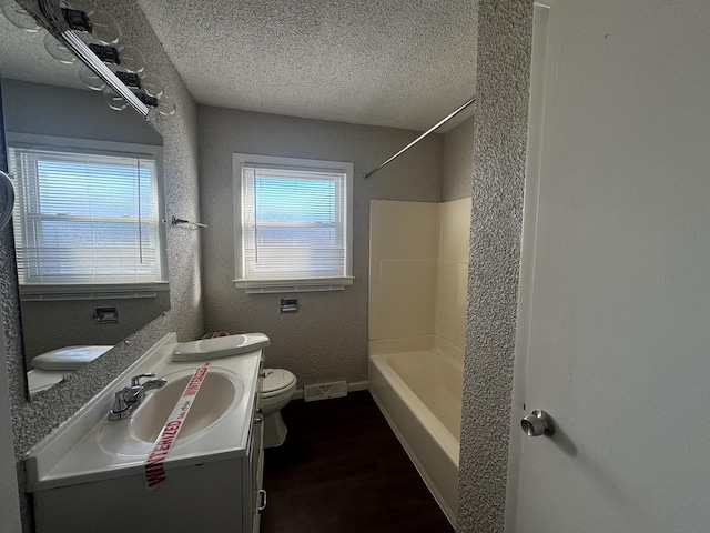 full bathroom featuring hardwood / wood-style flooring, a healthy amount of sunlight, toilet, and a textured ceiling