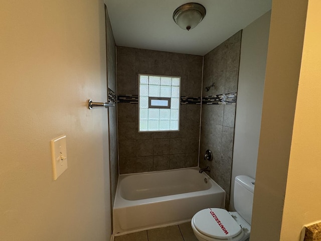 bathroom featuring tile patterned flooring, tiled shower / bath combo, and toilet