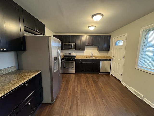 kitchen featuring light stone countertops, sink, dark hardwood / wood-style floors, and appliances with stainless steel finishes