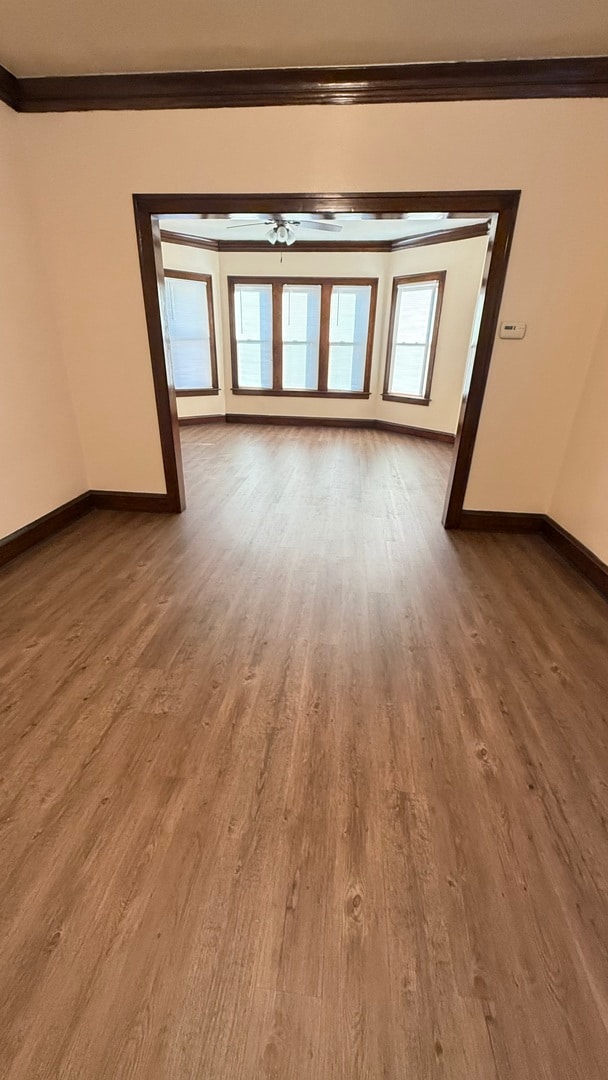 unfurnished room featuring wood-type flooring, ceiling fan, and ornamental molding