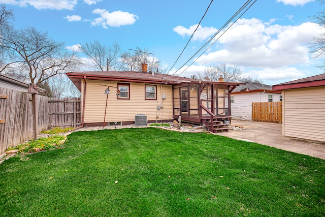 rear view of house featuring a deck, central AC unit, a patio area, a sunroom, and a yard