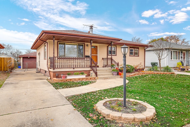 view of front facade with a front yard, covered porch, an outdoor structure, and a garage