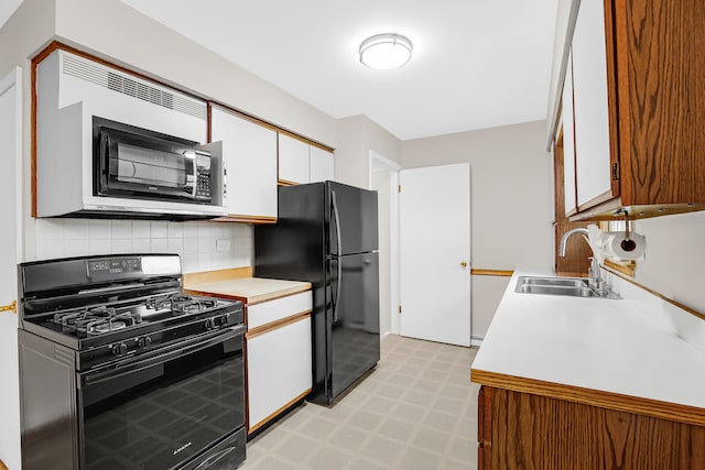 kitchen featuring sink, backsplash, white cabinetry, and black appliances