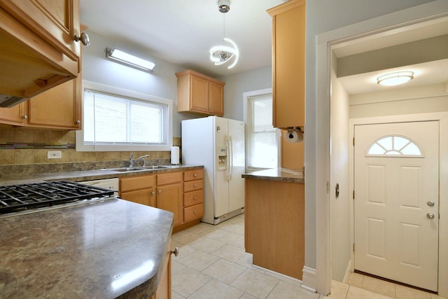 kitchen with plenty of natural light, white fridge with ice dispenser, sink, and decorative light fixtures