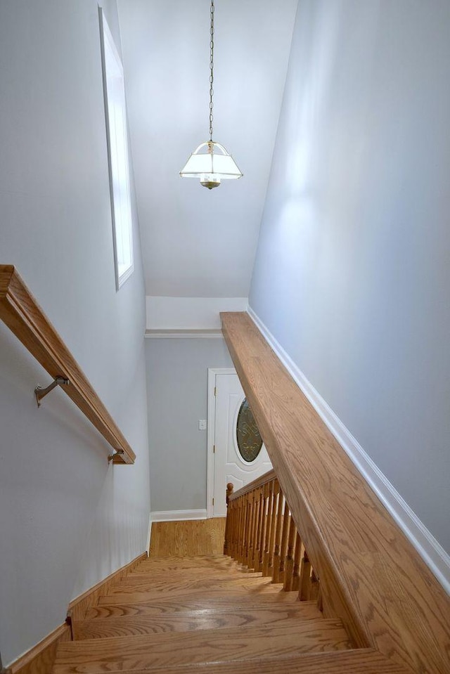 stairs with wood-type flooring and vaulted ceiling