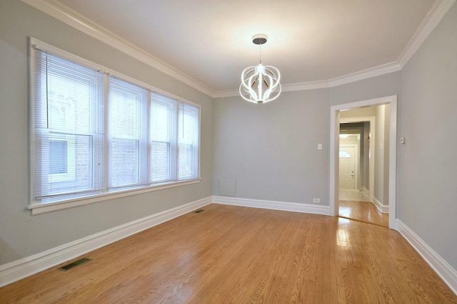 empty room featuring ornamental molding, light hardwood / wood-style flooring, and a notable chandelier