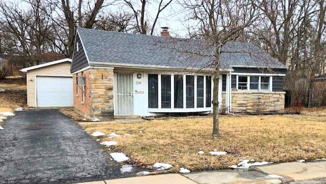 ranch-style home with aphalt driveway, a garage, a shingled roof, stone siding, and a chimney