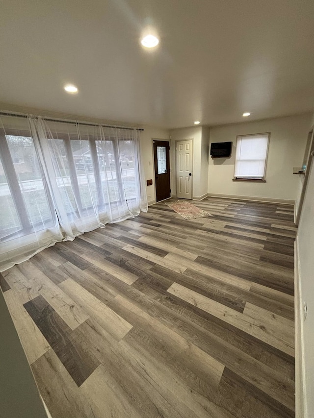 unfurnished living room featuring wood-type flooring and a wall unit AC