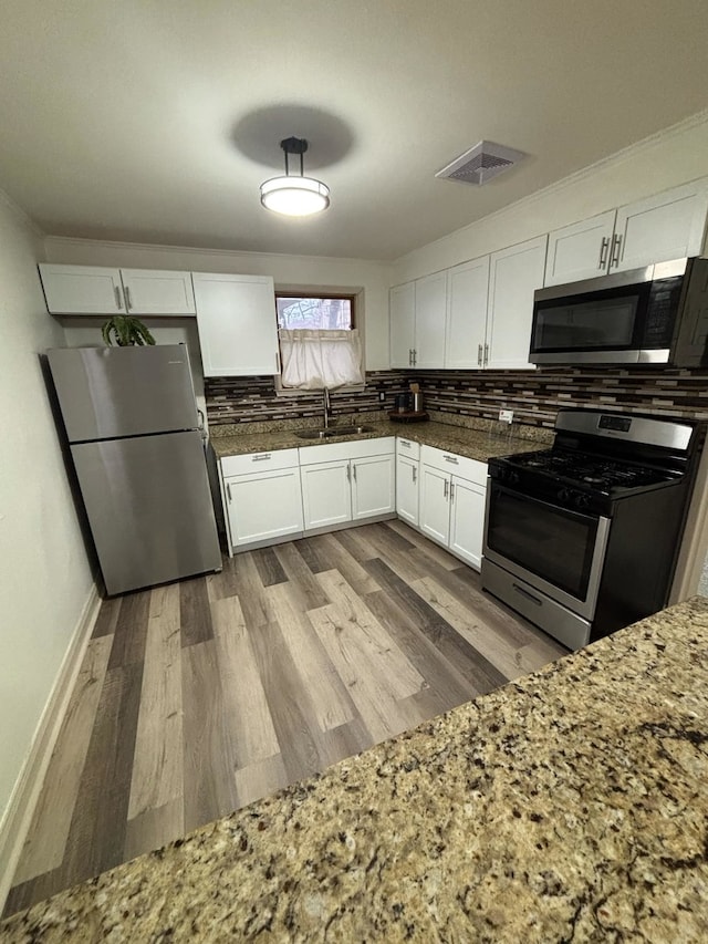 kitchen featuring decorative backsplash, appliances with stainless steel finishes, light wood-type flooring, and white cabinetry