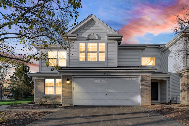 traditional-style house with an attached garage, driveway, and brick siding