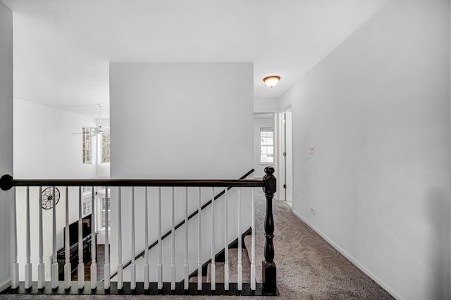 corridor with baseboards, carpet flooring, and an upstairs landing