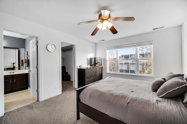 bedroom with visible vents, a sink, a walk in closet, and light colored carpet