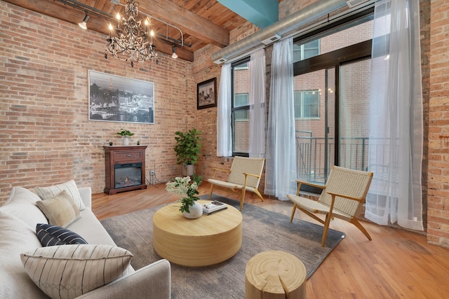 living room featuring wooden ceiling, an inviting chandelier, beamed ceiling, light hardwood / wood-style floors, and brick wall