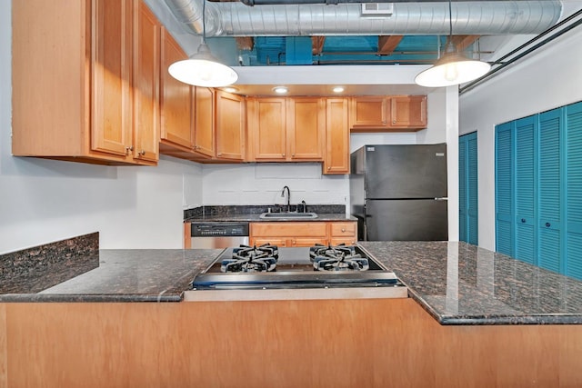 kitchen with dark stone countertops, sink, hanging light fixtures, and stainless steel appliances