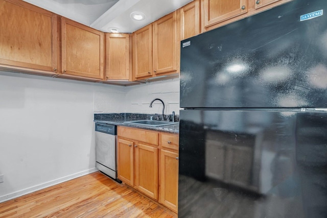 kitchen featuring tasteful backsplash, black fridge, stainless steel dishwasher, sink, and light hardwood / wood-style flooring