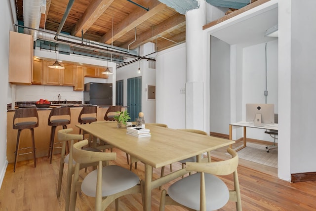 dining room with beamed ceiling, light wood-type flooring, sink, and wood ceiling