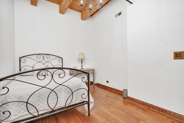 bedroom featuring beam ceiling and light hardwood / wood-style floors