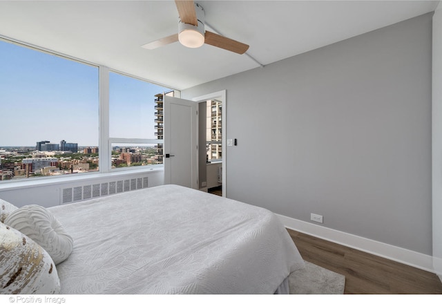 bedroom with ceiling fan, radiator heating unit, and wood-type flooring